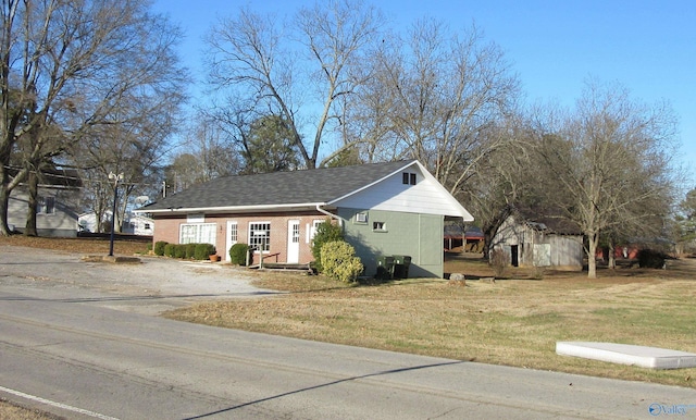 view of front facade featuring brick siding, a front yard, and roof with shingles