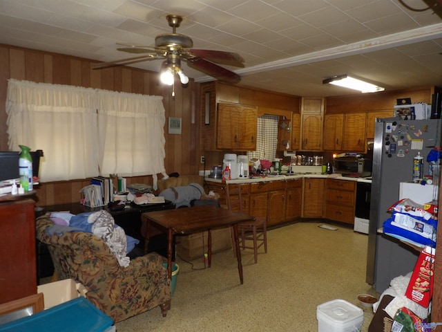 kitchen with white range, stainless steel fridge, wooden walls, and ceiling fan