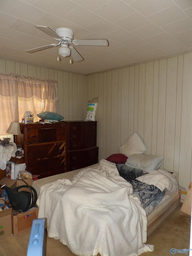 bedroom with light carpet, wood walls, and ceiling fan