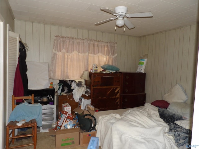 bedroom with wooden walls, carpet, and ceiling fan