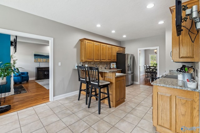 2801 Mountain View Dr, Southside, AL 35907 - kitchen with stainless steel refrigerator with ice dispenser, a peninsula, recessed lighting, light tile patterned flooring, and a breakfast bar area