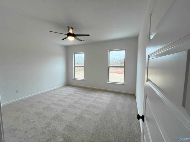 carpeted spare room featuring a ceiling fan and baseboards