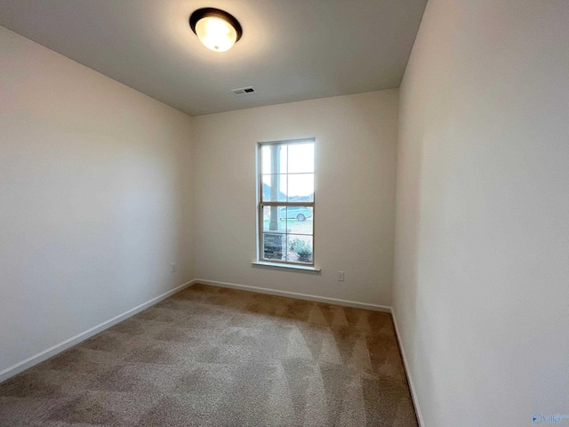 carpeted spare room featuring visible vents and baseboards