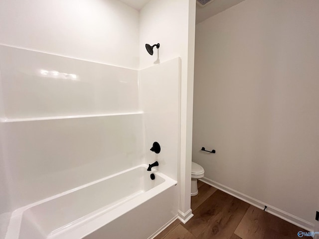 bathroom featuring bathtub / shower combination, baseboards, toilet, and wood finished floors