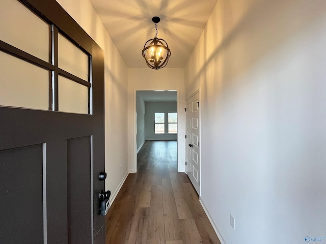 interior space with an inviting chandelier, baseboards, and wood finished floors