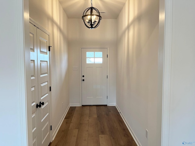 entryway with a notable chandelier, dark wood finished floors, and baseboards