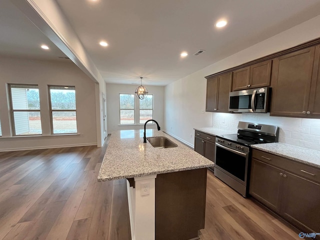 kitchen with visible vents, decorative backsplash, appliances with stainless steel finishes, a sink, and light stone countertops