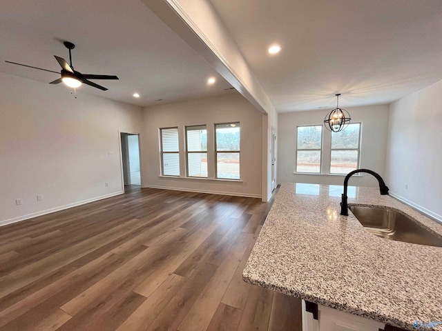 kitchen featuring dark wood-type flooring, light stone counters, open floor plan, and a sink