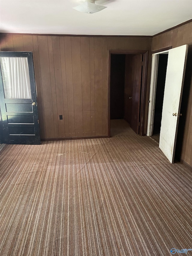 unfurnished room with wooden walls and carpet flooring