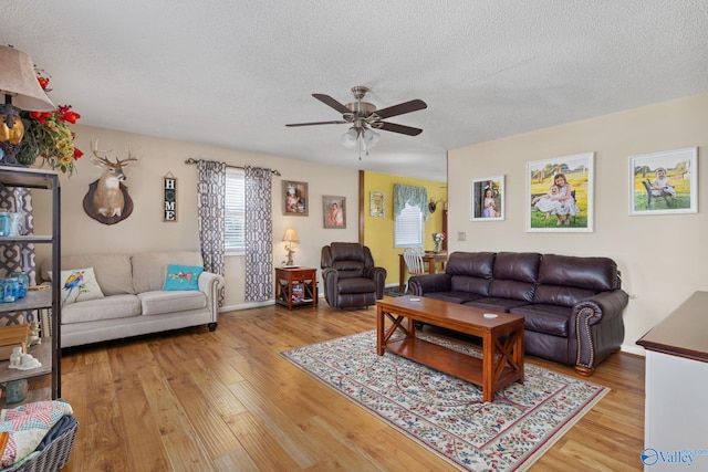 living room with a textured ceiling, wood-type flooring, and ceiling fan