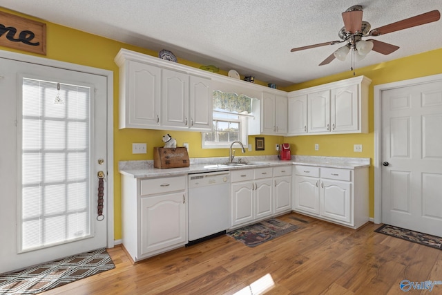 kitchen featuring white cabinetry, sink, white dishwasher, light hardwood / wood-style floors, and a textured ceiling