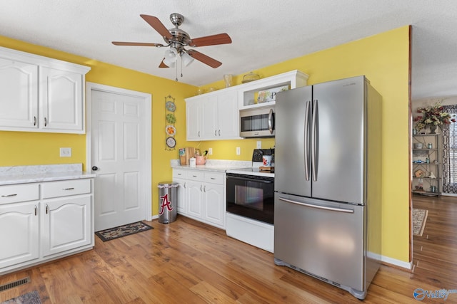 kitchen with white cabinetry, stainless steel appliances, light hardwood / wood-style floors, and a textured ceiling