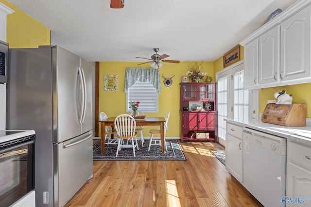 kitchen featuring range, light hardwood / wood-style flooring, stainless steel fridge, white dishwasher, and white cabinets