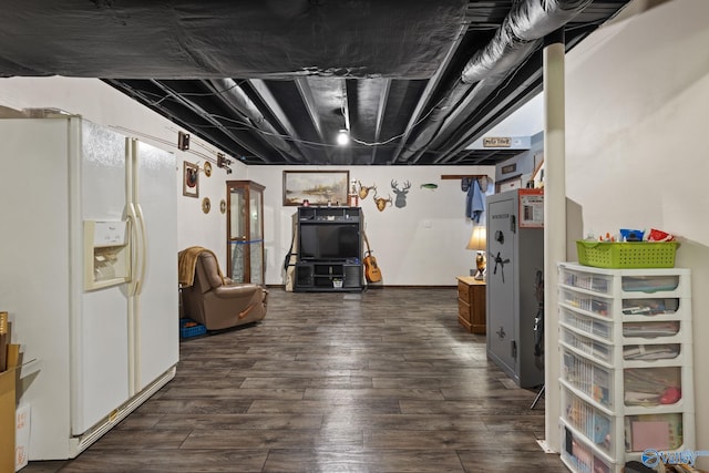 basement featuring white fridge with ice dispenser and dark wood-type flooring