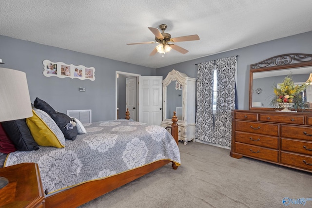 bedroom with ceiling fan, light carpet, and a textured ceiling