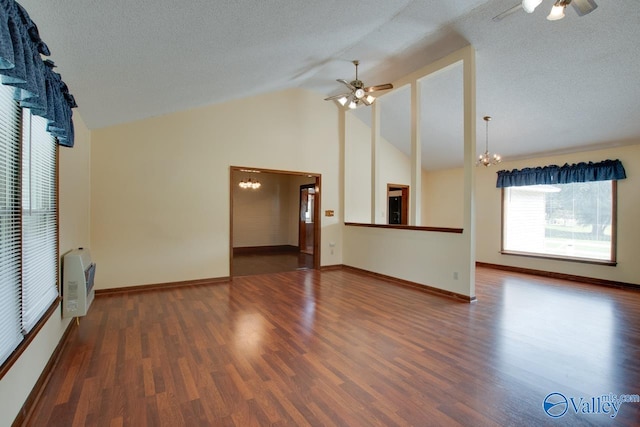 unfurnished living room featuring heating unit, a textured ceiling, dark hardwood / wood-style floors, high vaulted ceiling, and ceiling fan with notable chandelier