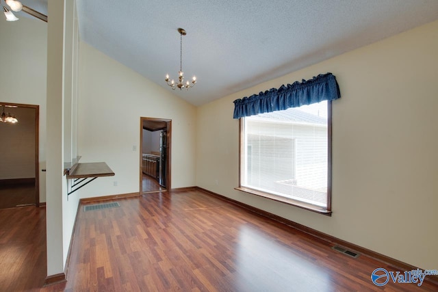 empty room featuring dark wood-type flooring, high vaulted ceiling, an inviting chandelier, and a textured ceiling