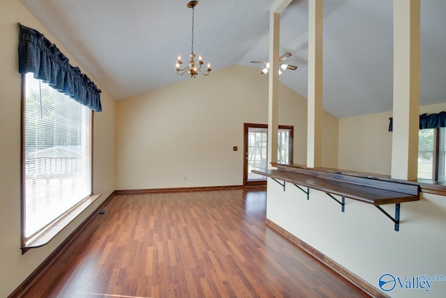 kitchen featuring pendant lighting, plenty of natural light, dark wood-type flooring, and vaulted ceiling