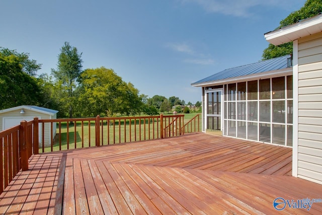 deck with a sunroom, a lawn, and a storage shed