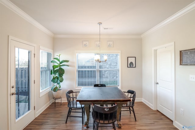 dining area featuring crown molding, dark hardwood / wood-style floors, and a notable chandelier