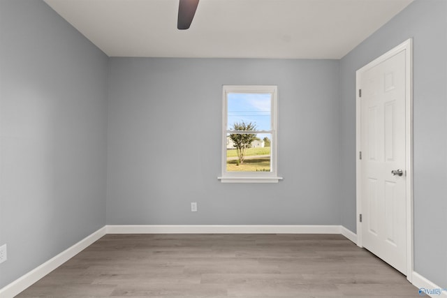 unfurnished room featuring light wood-type flooring, a ceiling fan, and baseboards