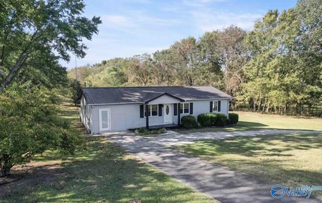 ranch-style home with a forest view, driveway, and a front yard