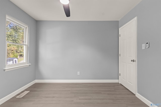 empty room featuring wood finished floors, visible vents, a ceiling fan, and baseboards