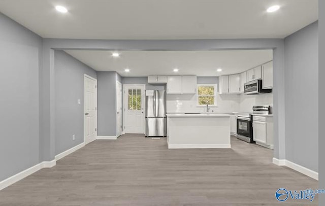 kitchen featuring white cabinets, stainless steel appliances, and light wood-style floors