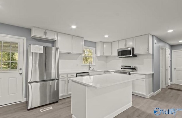 kitchen featuring appliances with stainless steel finishes, light countertops, white cabinetry, and light wood-style flooring