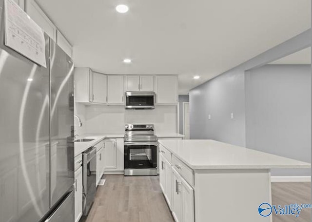 kitchen featuring stainless steel appliances, recessed lighting, light wood-style floors, light countertops, and a kitchen island