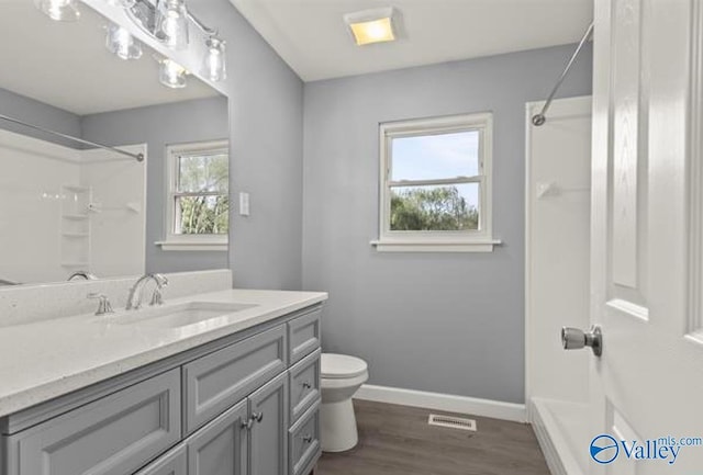 full bath featuring toilet, baseboards, visible vents, wood finished floors, and vanity