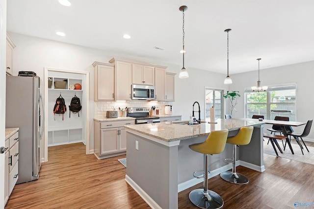 kitchen featuring a center island with sink, appliances with stainless steel finishes, light wood-type flooring, and sink