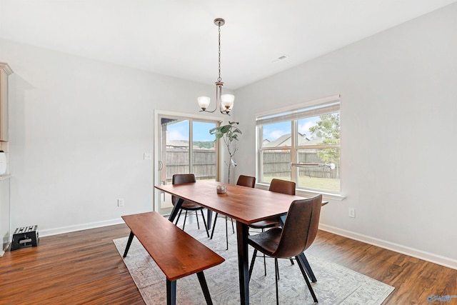 dining space featuring dark wood-type flooring and a notable chandelier