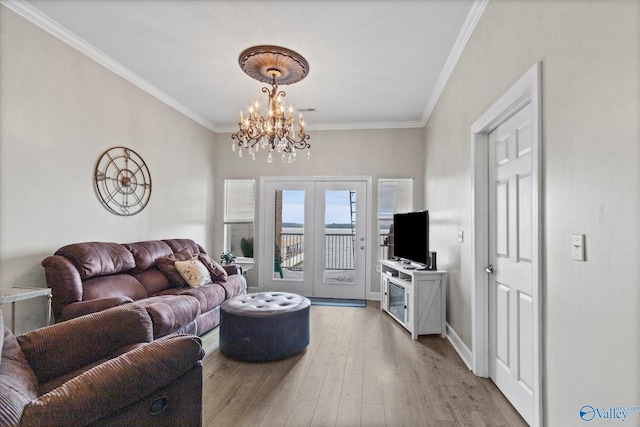 living area with french doors, ornamental molding, light wood-style flooring, and a chandelier