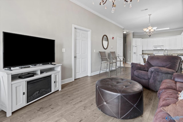 living room with baseboards, ornamental molding, light wood finished floors, and a notable chandelier
