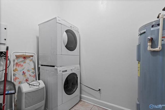 washroom featuring laundry area, tile patterned floors, baseboards, water heater, and stacked washer and clothes dryer