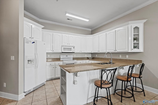 kitchen with a sink, white appliances, a kitchen breakfast bar, a peninsula, and baseboards