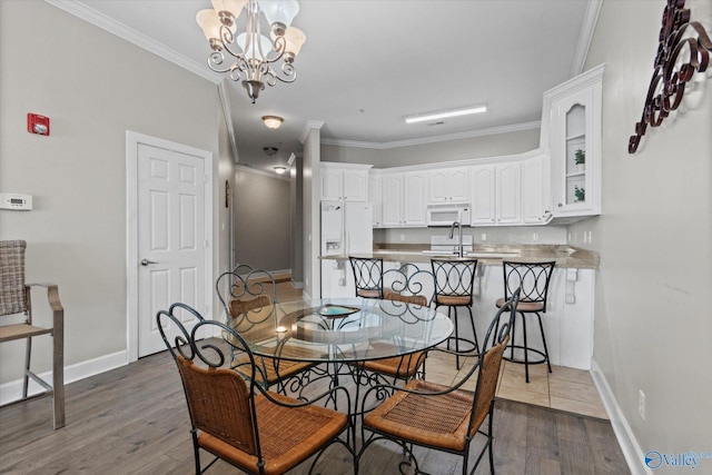 dining space with baseboards, ornamental molding, wood finished floors, and a notable chandelier