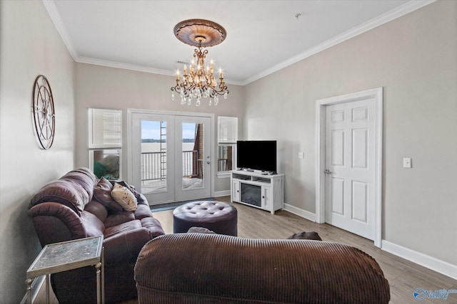 living room with crown molding, an inviting chandelier, light wood-style floors, and french doors