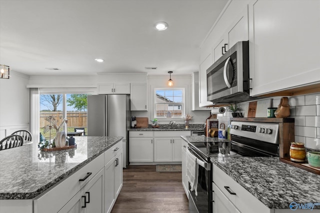 kitchen featuring dark wood-style flooring, visible vents, stainless steel appliances, and a healthy amount of sunlight