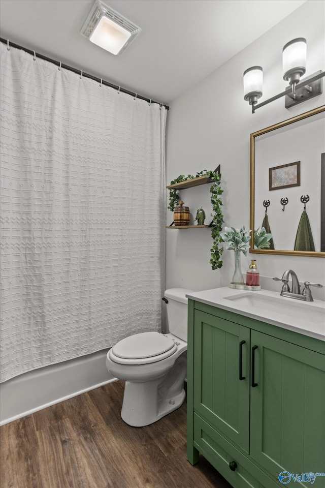 bathroom with vanity, toilet, visible vents, shower / bath combination with curtain, and wood finished floors