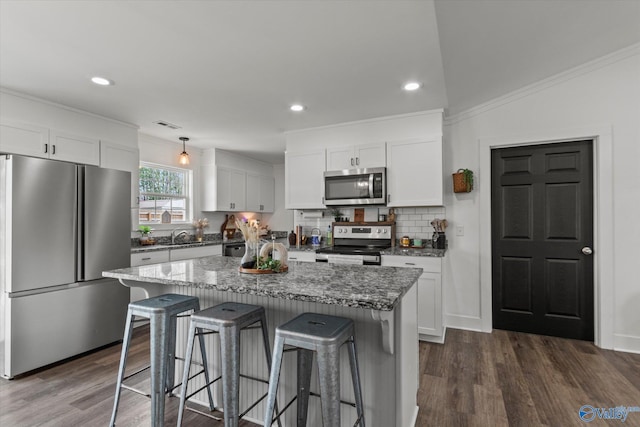 kitchen featuring white cabinets, stainless steel appliances, a breakfast bar, and a center island