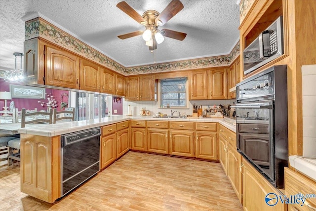 kitchen with kitchen peninsula, sink, light wood-type flooring, black appliances, and tile counters