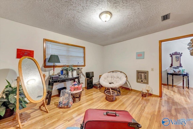 game room featuring wood-type flooring, a textured ceiling, and heating unit