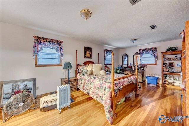 bedroom with a textured ceiling and wood-type flooring