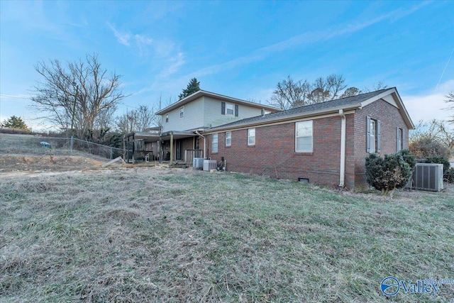 rear view of property featuring a lawn and central air condition unit