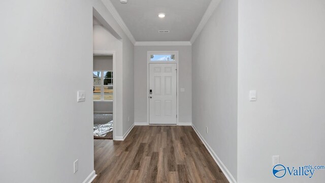 interior space with baseboards, visible vents, ornamental molding, and wood finished floors