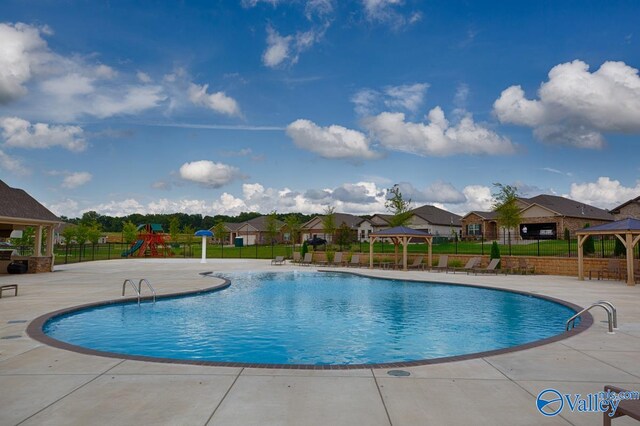 community pool featuring fence, playground community, a gazebo, a residential view, and a patio area