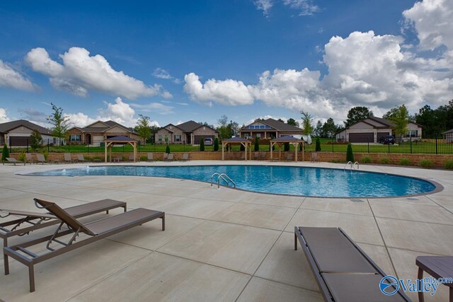 pool featuring a patio area, a residential view, a gazebo, and fence