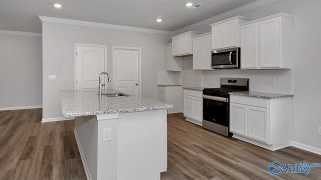 kitchen with stainless steel appliances, decorative backsplash, a sink, an island with sink, and white cabinets